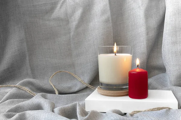 Beyaz bir kitabın üzerinde duran iki mum. Mumlu gri kumaş arkaplan