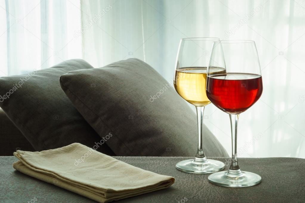 two glasses of red and white wine in a living room