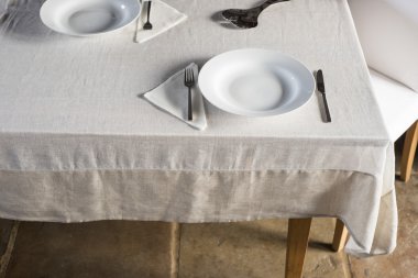 Beyaz keten kaplı masaya düzenlenmiş yemek setleri