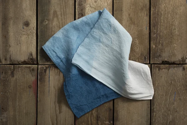 Tissu ou lin bleu dégradé plié sur la surface du panneau en bois — Photo