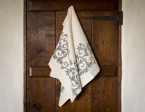Serviette blanche avec motif floral gris accroché à la porte en bois — Photo