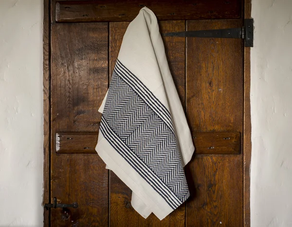 White Towel with Black Herringbone and Stripes Hanging on  Door