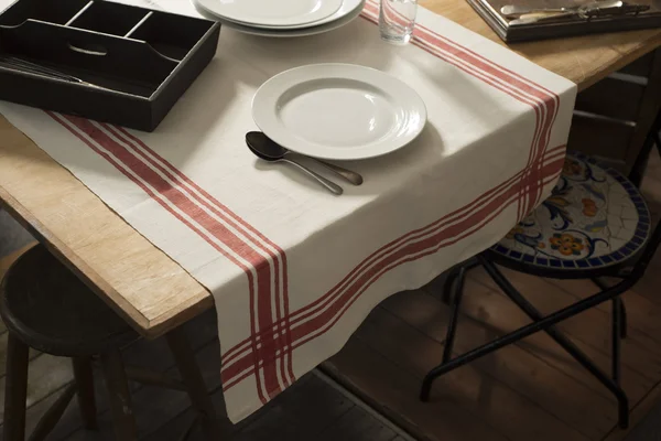 Ubrus s tištěnou červenými pruhy na stůl s Dinnerwar — Stock fotografie