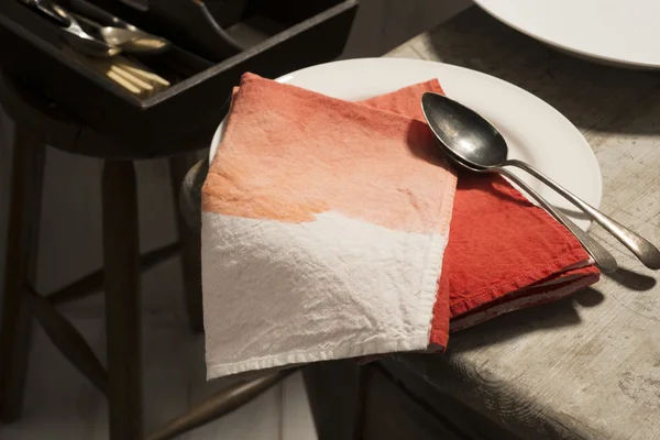 Színátmenet piros szalvéta és a kanál a tányér fehér — Stock Fotó
