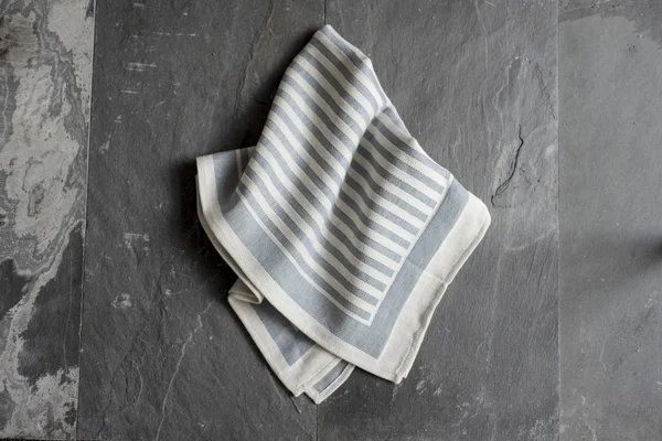 Серое полотенце или салфетка на серой каменной поверхности — стоковое фото