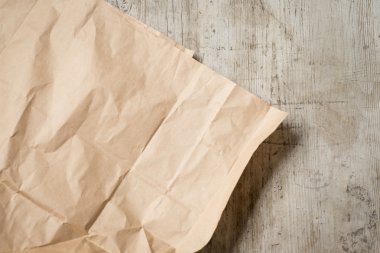 Yıpranmış, ahşap yüzeyde buruşuk kahverengi kağıt