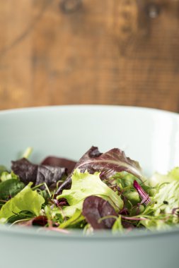 ahşap arka plan mavi bir kase karışık yaprak salata
