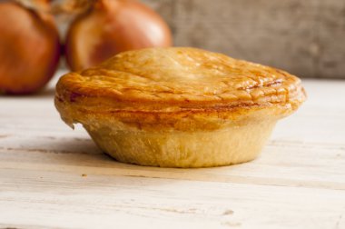 Pişmiş pasta ve pürüzsüz bir ahşap yüzey üzerinde soğan