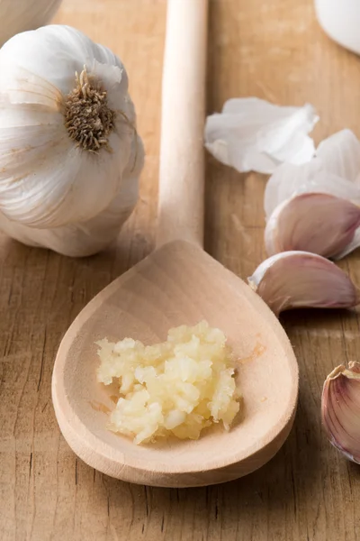 Crushed Garlic on Wooden Spoon Beside Unpeeled Cloves — Stock Photo, Image