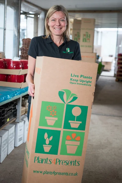 Mujer sonriente llevando una caja de cartón grande — Foto de Stock