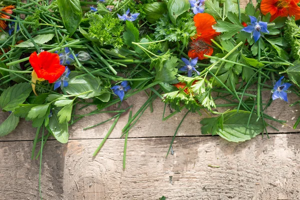 Herbes mélangées et fleurs comestibles sur table en bois — Photo