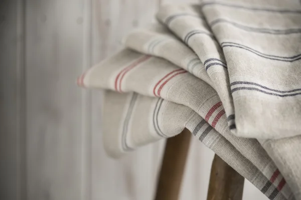 Empilement de linge rayé sur un tabouret en bois — Photo