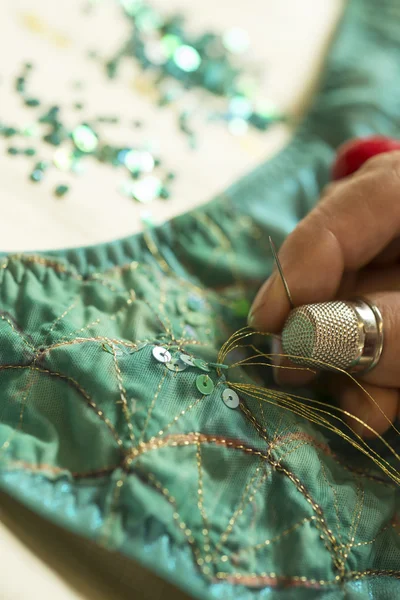 Золотая нить сквозь секин на зеленой одежде — стоковое фото