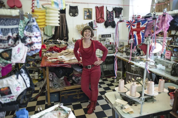 Donna in rosso in piedi in mezzo al negozio di sartoria — Foto Stock