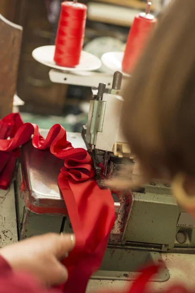 Красная ткань в швейной машине от швеи — стоковое фото