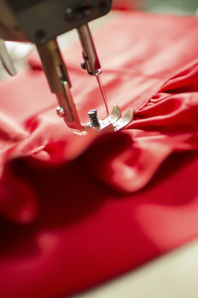 Крупный план иглы швейной машины, пристегивающей красную ткань — стоковое фото