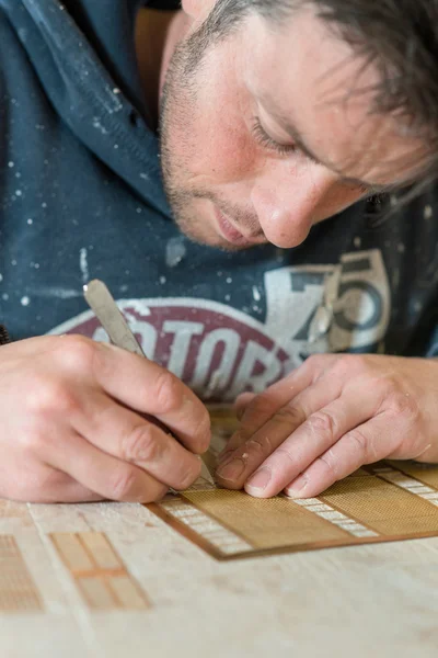 Uomo con coltello di precisione e matita che lavora sul tavolo da disegno — Foto Stock