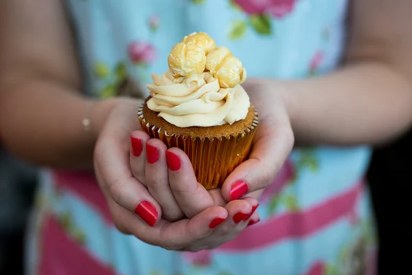 Vrouw in Floral dress met gelakte nagels houden popcorn cupcake — Stockfoto