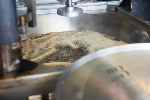 Churros cozinhar em óleo quente em um grande recipiente de metal — Fotografia de Stock