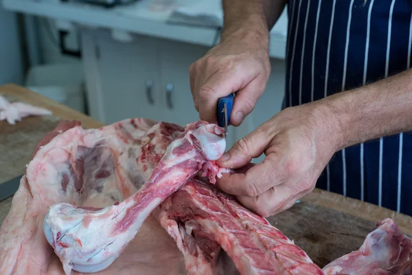 Řezník nožem krájet maso — Stock fotografie