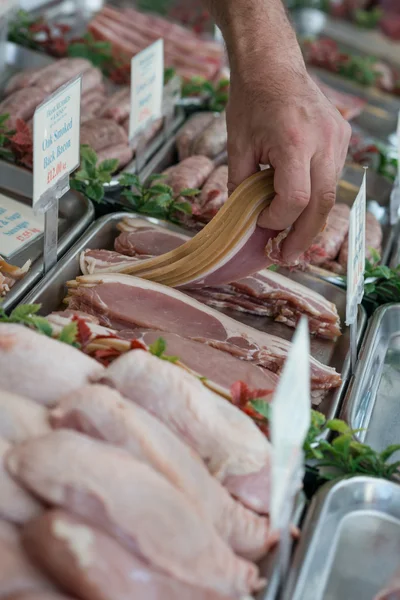 Butcher picking up bacon — Stock Photo, Image