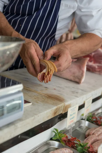 Açougueiro contando fatias de bacon — Fotografia de Stock