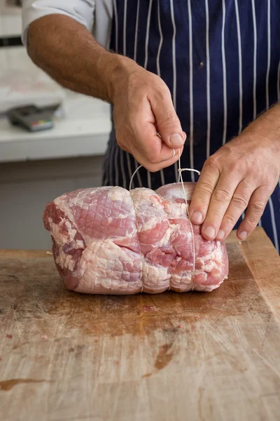 Butcher tying up a joint of ham — Stock Photo, Image