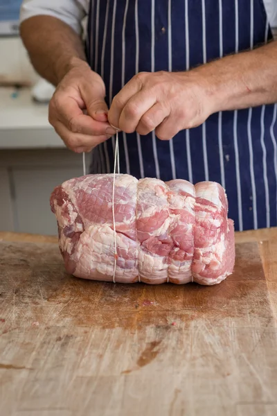 Butcher demonstrating how to tie a joint of ham with string — Stock Photo, Image