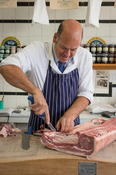 Carniceiro esculpindo um rack de carne com uma faca afiada — Fotografia de Stock