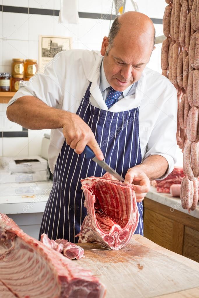 Butcher in shop butchering a rack of lamb