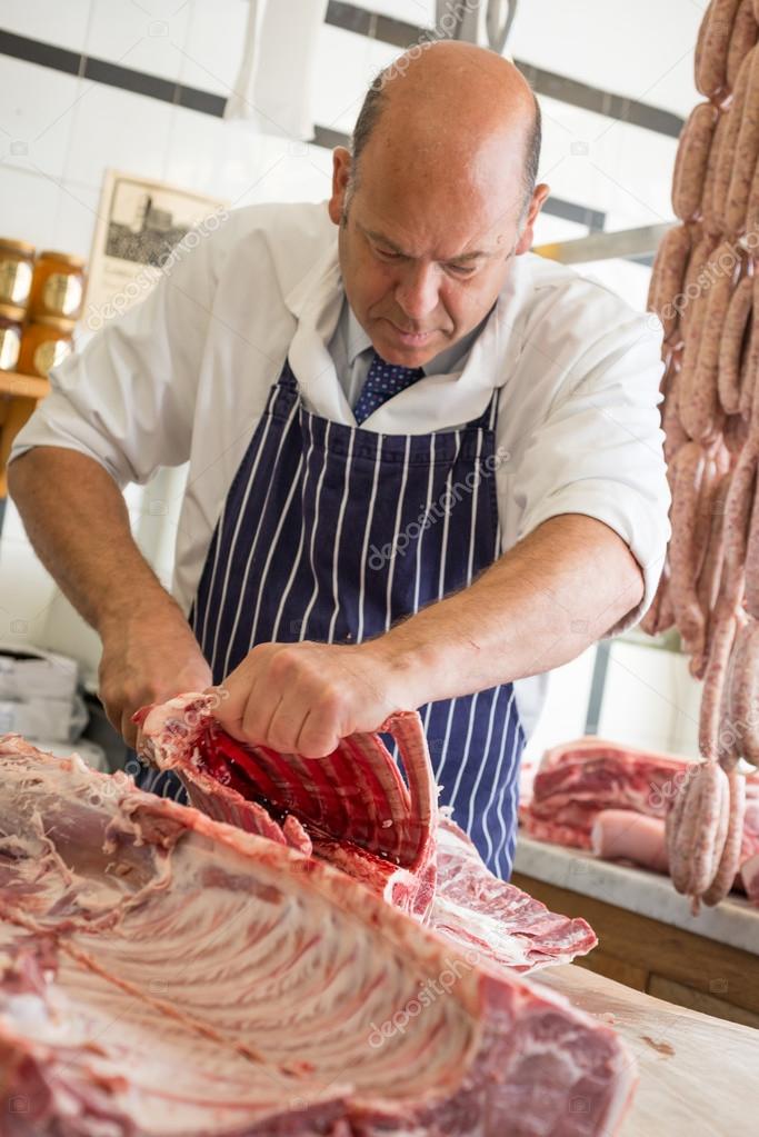 Butcher and rack of lamb using his hands to separate cutlets