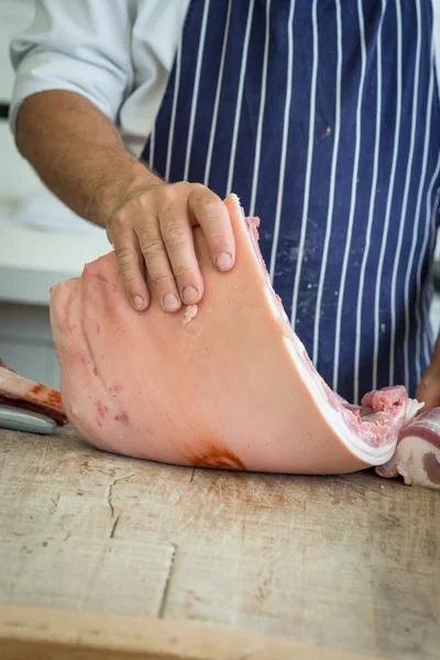Butcher Lifting up a belly of pork — Stock Photo, Image