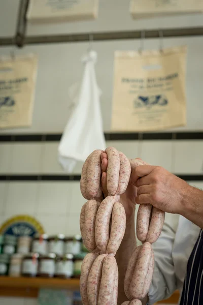 Açougueiro segurando uma série de salsichas — Fotografia de Stock