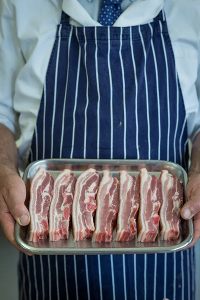 Butcher in blue and white apron with a tray of raw meat — Stock Photo, Image