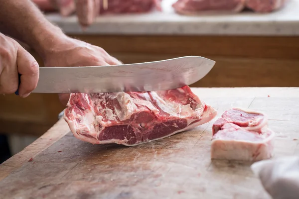 Carving lamb steaks with a large knife — Stock Photo, Image