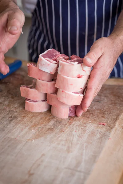 Butchers hands with lamb chops on a wooden board — Stock Photo, Image