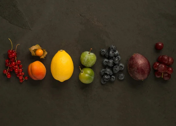 Reihe bunter Früchte auf dunklem Hintergrund Stockbild