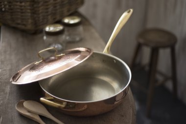 Partially Covered Copper Frying Pan on Edge of Wooden Counter