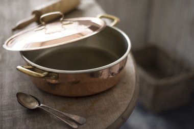 Small Partially Covered Copper Pot on Edge of Wooden Counter