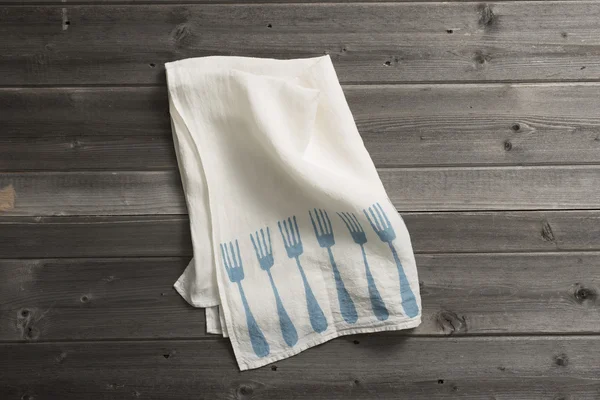 Olded servet met blauwe vork patroon op houten oppervlak — Stockfoto