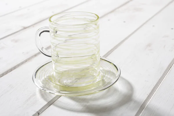 Tasse en cristal et soucoupe rayée de jaune sur panneau en bois — Photo