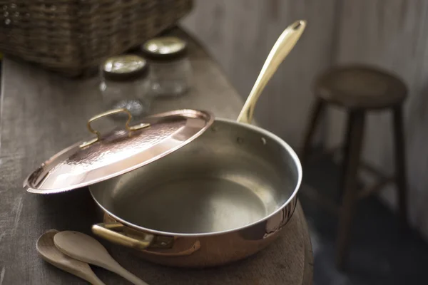 Partially Covered Copper Frying Pan on Edge of Wooden Counter