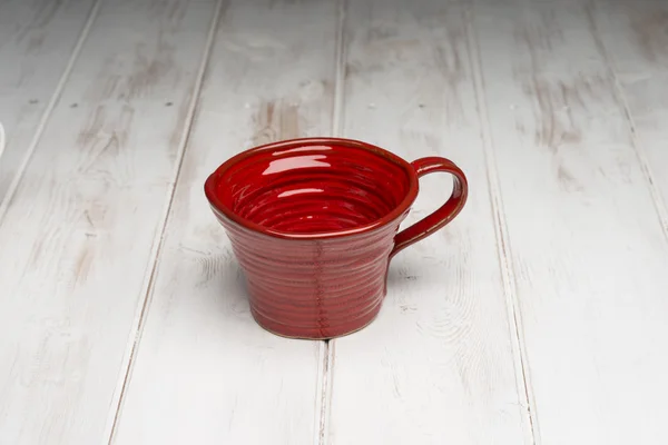 Taza hecha a mano roja vacía en la superficie del panel de madera blanca — Foto de Stock