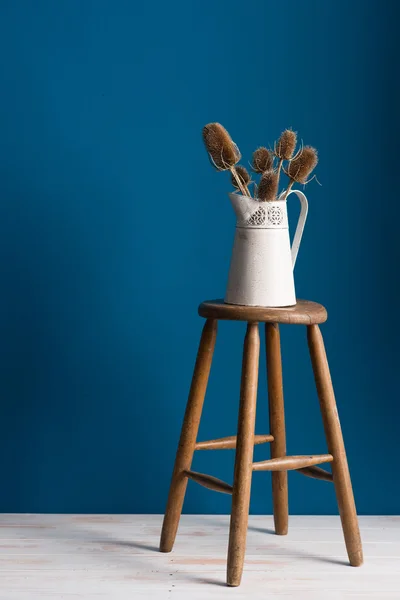 Alte Krug-Vase auf einem Hocker vor blauem Hintergrund — Stockfoto