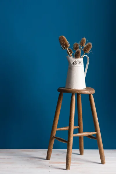 Vieux vase Pitcher sur un tabouret sur fond bleu — Photo