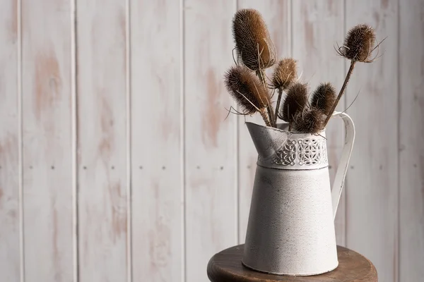 Chardons séchés dans un vase Pitcher sur tabouret en bois — Photo