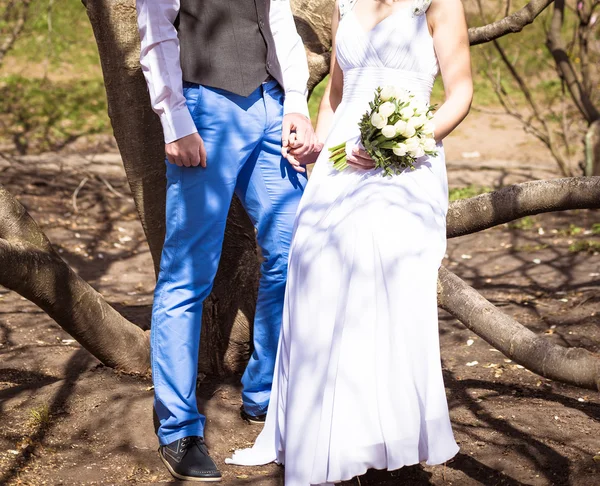 Щаслива наречена і наречена позує в парку біля весняних квітів на день весілля — стокове фото