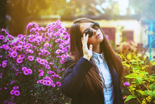 Woman in black glasses near flowerbed — Stock Photo, Image