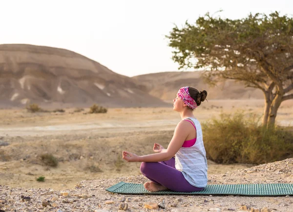 Ung kvinna gör yoga i öknen vid soluppgång tid — Stockfoto