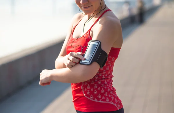 Спортивная женщина пользуется телефоном во время тренировок на городской набережной рано утром — стоковое фото
